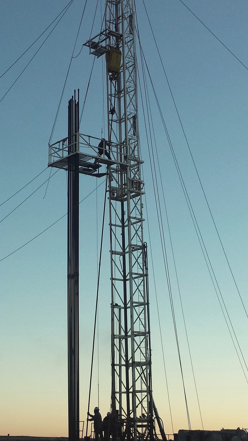 A drilling derrick against the last light of the day